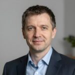 Портрет уверенного и дружелюбного руководителя издательства Новый РусЛит на нейтральном размытом фоне