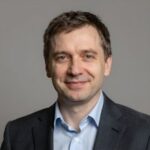 Портрет уверенного и дружелюбного руководителя издательства Новый РусЛит на нейтральном размытом фоне