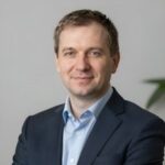 Портрет уверенного и дружелюбного руководителя издательства Новый РусЛит на нейтральном размытом фоне